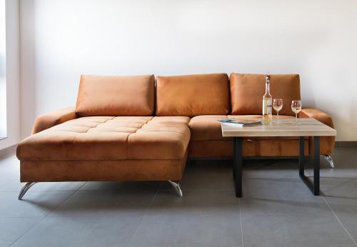 a brown couch with a table and two glasses of wine at Apartamenty Dworcowa 60 in Gliwice
