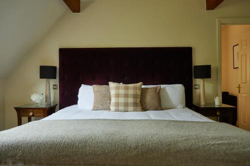 a bedroom with a large bed with two lamps on tables at The Slaughters Country Inn in Lower Slaughter