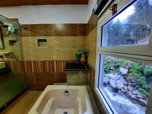 a bathroom with a bath tub and a window at Blue Water Resort Kalam in Kārandūkai