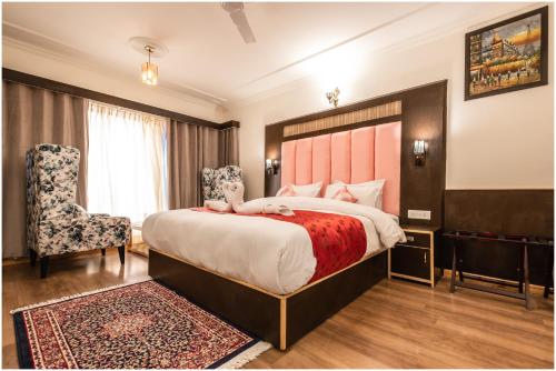 um quarto de hotel com uma cama grande e uma cadeira em Sangaylay palace em Leh