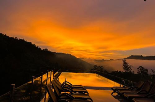 a group of chairs sitting around a pool with a sunset at Morning Dew Boutique Hotel Ella in Ella