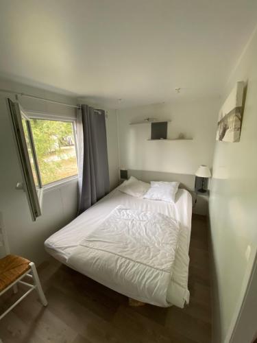 a white bed in a room with a window at Mobilhome Santerre in Châtillon-sur-Broué