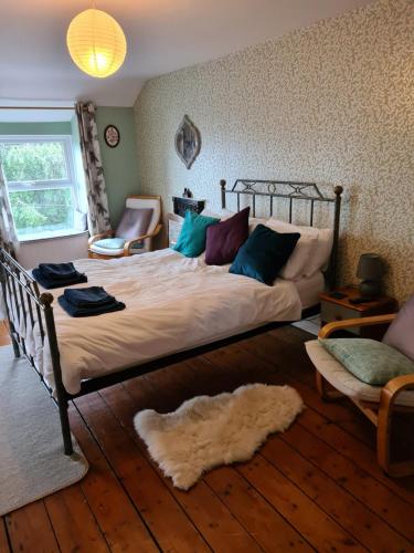 a bedroom with a large bed with a rug on the floor at North Wales Cosy Cottage with views near Eryri Snowdonia in Nantlle