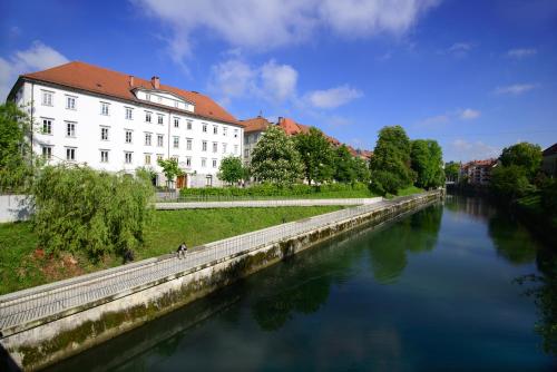 a river in front of a large white building at Galeria River in Ljubljana