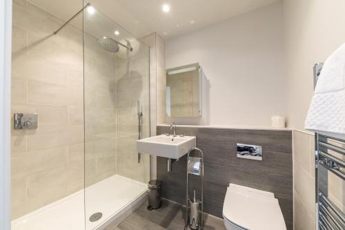 a bathroom with a shower and a sink and a toilet at 8 Challacombe - Luxury Apartment at Byron Woolacombe, only 4 minute walk to Woolacombe Beach! in Woolacombe