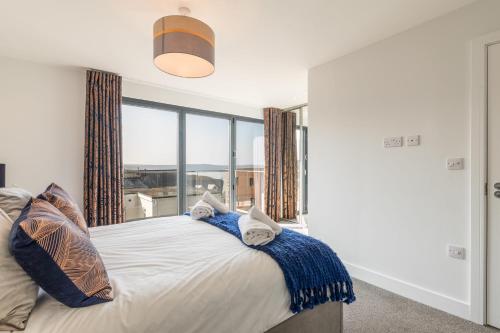 a bedroom with a bed with a large window at 8 Challacombe - Luxury Apartment at Byron Woolacombe, only 4 minute walk to Woolacombe Beach! in Woolacombe
