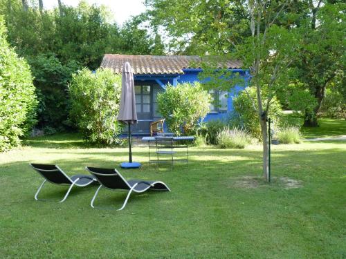 two chairs and an umbrella and a table in a yard at Les Gîtes du Domaine de Rhodes in Avignon
