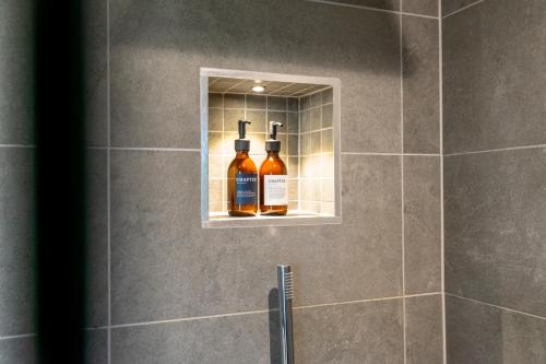 two bottles of alcohol are on a shelf in a shower at Apartment 304 @ Ryedale House in York