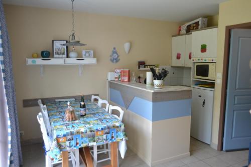 uma cozinha com uma mesa com cadeiras e um micro-ondas em La Maison Rose em Fort-Mahon-Plage