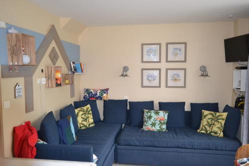 um sofá azul com almofadas numa sala de estar em La Maison Rose em Fort-Mahon-Plage