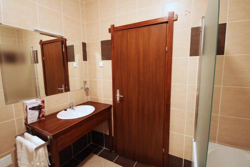 a bathroom with a sink and a wooden door at Hotel Lug in Osijek