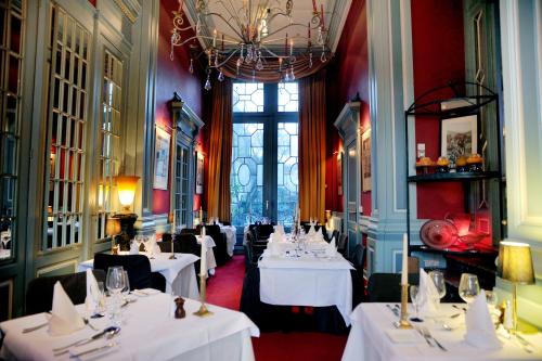 um restaurante com mesas e cadeiras brancas e um lustre em Home Fleuri Guesthouse em Bruges