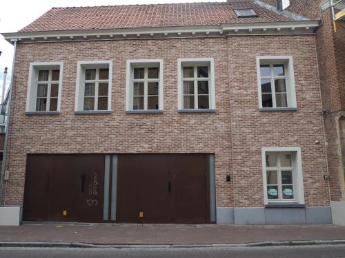 a brick building with two garage doors and windows at Rubbensloft in Zele