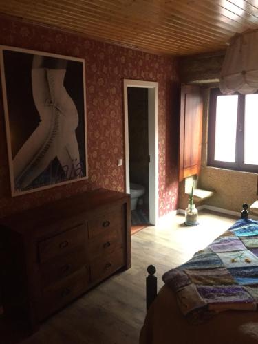 a bedroom with a bed and a dresser and a window at Casa do Castelo de Celorico in Celorico da Beira