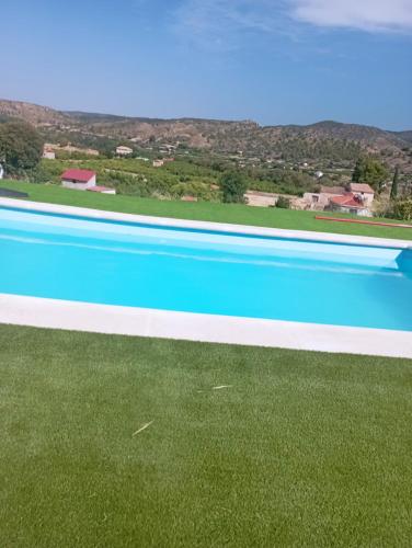 a large swimming pool with blue water and green grass at Cabezo Buñuel Hostal in Calanda