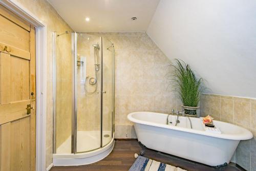 a bathroom with a bath tub and a shower at The Coach House by Bloom Stays in Harrietsham