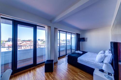 a bedroom with a bed and large windows at Sarroglia Hotel in Bucharest