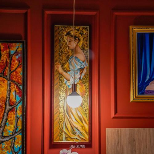 a painting of a woman hanging on a red wall at Jata Hotel in Tirana