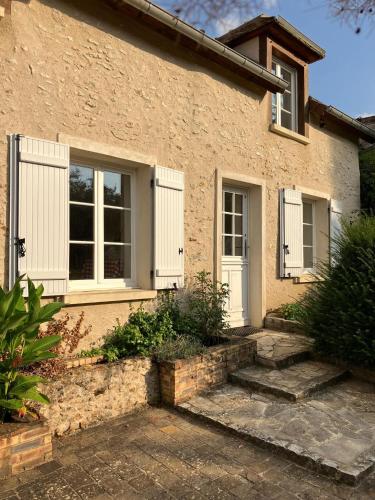 une maison en briques avec une porte et des fenêtres blanches dans l'établissement La petite maison de la vallée, à Bazainville