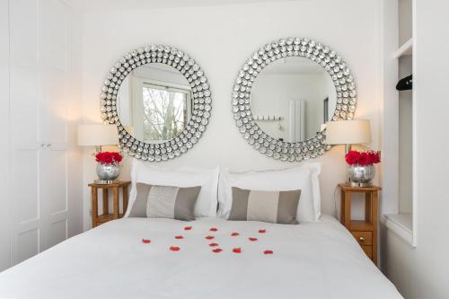 a bedroom with two mirrors above a bed with red roses at The Nestle House in Winchester