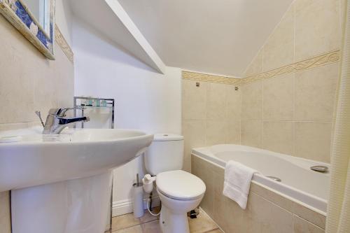 Talbot Woods Villa في بورنموث: حمام مع حوض ومرحاض وحوض استحمام