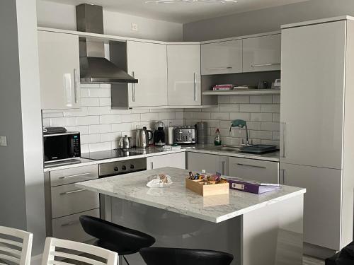 uma cozinha com armários brancos e uma bancada em Atlantic Port Retreat em Portstewart