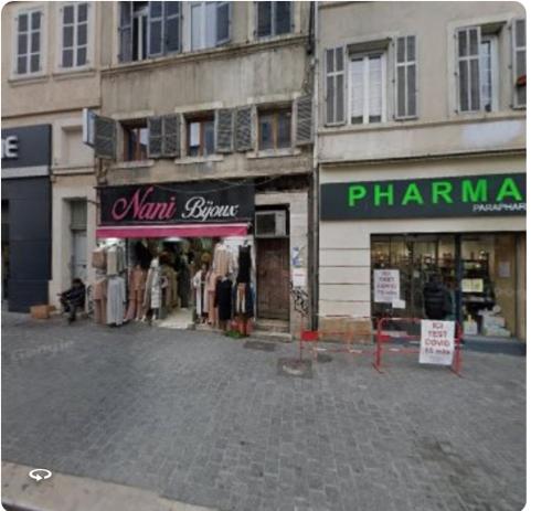 a street with a clothing store and a pharmacy at Joli T4 rénové climatisé entre St Charles/le Vieux-port in Marseille