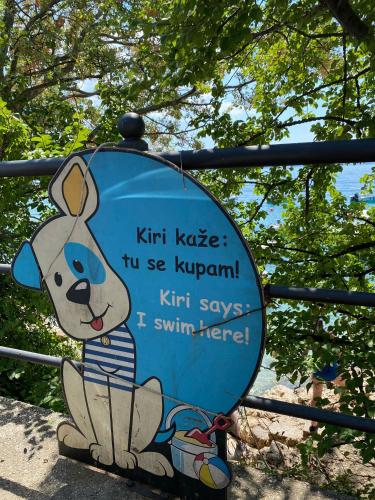a sign with a cartoon dog sitting on a gate at Rosmarin&Olive Premium Mobile Homes in Selce