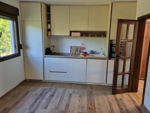 cocina con armarios blancos y suelo de madera en Green, en Andrijevica
