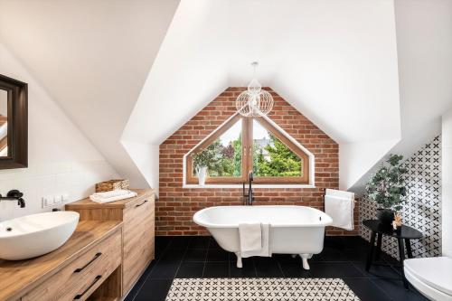 a bathroom with a white tub and a brick wall at Grabowa 19 in Brzozówka