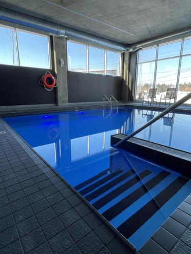 een zwembad met blauw water in een gebouw bij Grand Hotel TiMES Blainville-Mirabel in Blainville