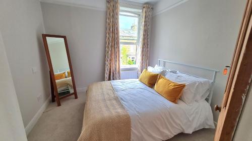 a bedroom with a bed with yellow pillows and a mirror at Brylie House, Large Central family home in Skipton