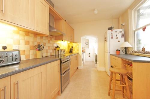 a large kitchen with wooden cabinets and a refrigerator at Brylie House, Large Central family home in Skipton