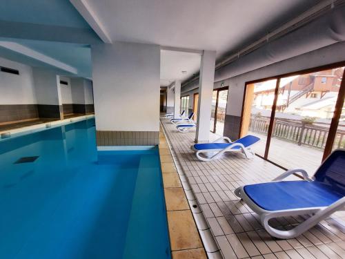 uma piscina com uma fila de cadeiras ao lado em T2/3 6pers & pied des pistes & piscine chauffée em Vars