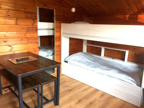 - une chambre avec des lits superposés et une table dans l'établissement Chalet en bois "Le Libellule", à Sigean