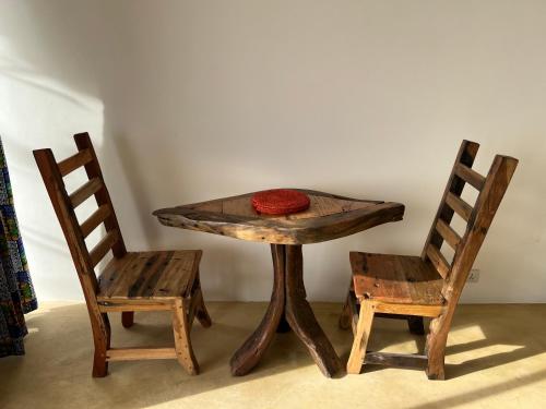 a wooden table with two chairs and a red hat on it at The View of Zanzibar in Michamvi