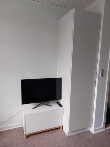 a living room with a tv on a white cabinet at Stuelejlighed med have og overdækket terrasse in Odense
