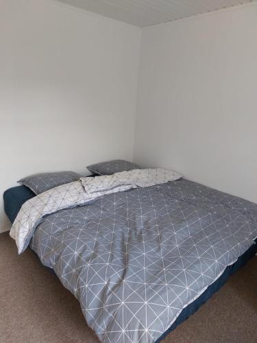 a bed with a blue comforter and two pillows at Stuelejlighed med have og overdækket terrasse in Odense