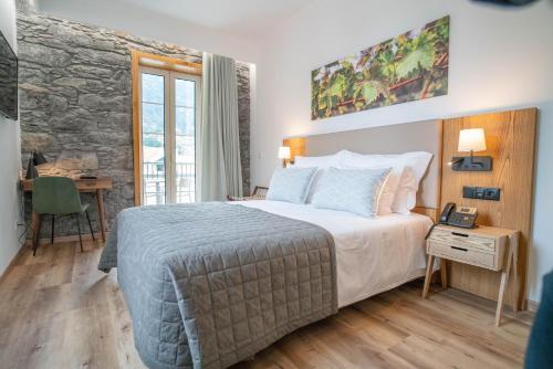 um quarto de hotel com uma cama, uma secretária e uma janela em Quinta Vale Vitis em São Vicente