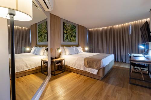a hotel room with two beds and a desk at Hotel Cassino Tower São José do Rio Preto by Nacional Inn in Sao Jose do Rio Preto