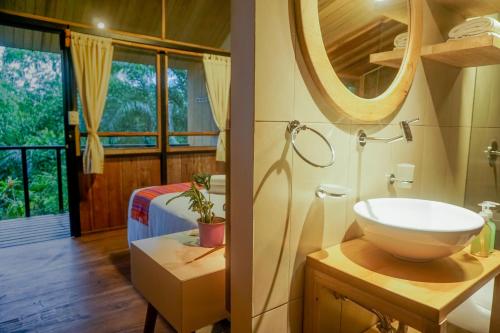 a bathroom with a sink and a mirror and a bed at Pacha Eco Lodge Glamping & Hotel in Archidona