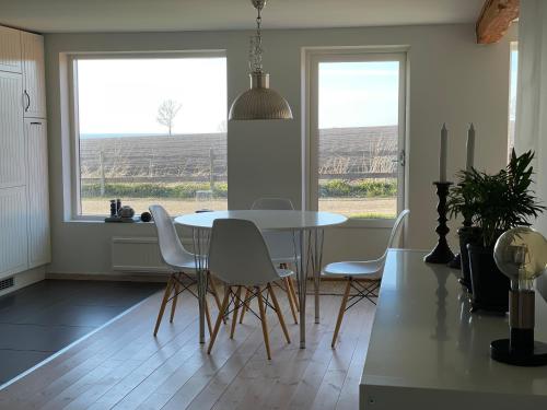 a dining room with a white table and chairs and windows at Ingridgården in Båstad