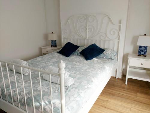 a white bed with blue pillows in a bedroom at Cosy Central Canterbury - Modern Victorian in Kent