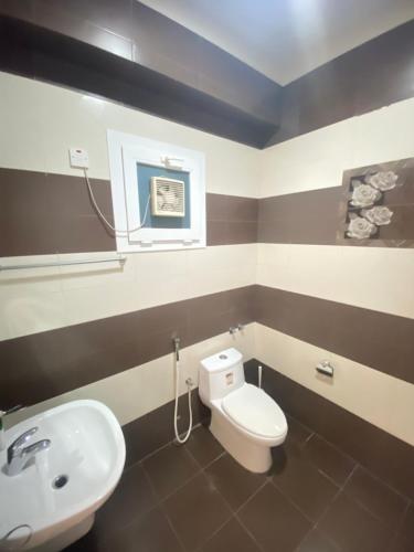 a bathroom with a white toilet and a sink at SHAIKHA villa in Umm al ‘Amad