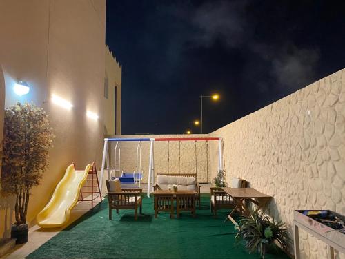 d'une terrasse avec une table, des chaises et un toboggan. dans l'établissement SHAIKHA villa, à Umm al ‘Amad