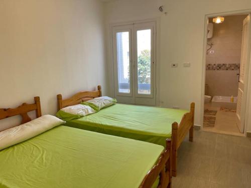two green beds in a room with a bathroom at Stunning Beachfront Villa on North Coast Mediterranean in Dawwār Abū Maḩrūs