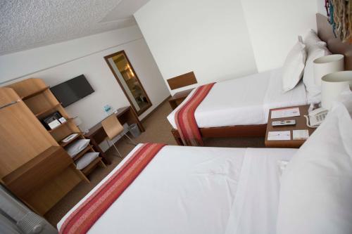 a hotel room with a bedroom with a bed and a desk at Tierra Viva Puno Plaza in Puno