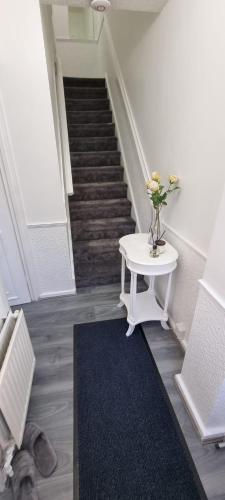 a staircase with a table with a vase of flowers on it at Glamorous room with WiFi and Netflix in Leeds