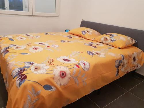 Una cama con una manta amarilla con flores. en Kingu's Apartment en Golem