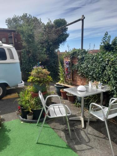 a patio with a table and chairs and plants at Janet Hale Studios, Garden Apartment in Glastonbury